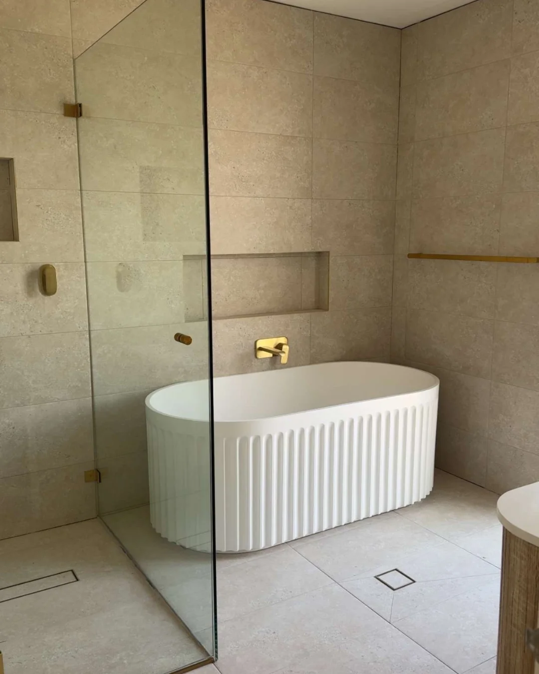 Modern bathroom design with white tiles and gold fixtures showcasing Verona Ceramic's premium flooring and renovation materials.