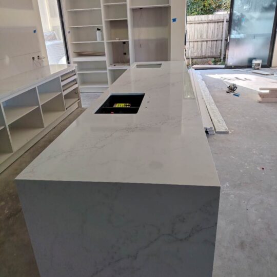 Modern kitchen featuring white engineered stone benchtop and cabinetry.