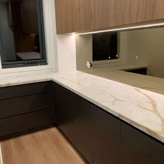 Kitchen stone benchtop and cabinetry showcasing Verona Ceramic's engineered stone and timber flooring.