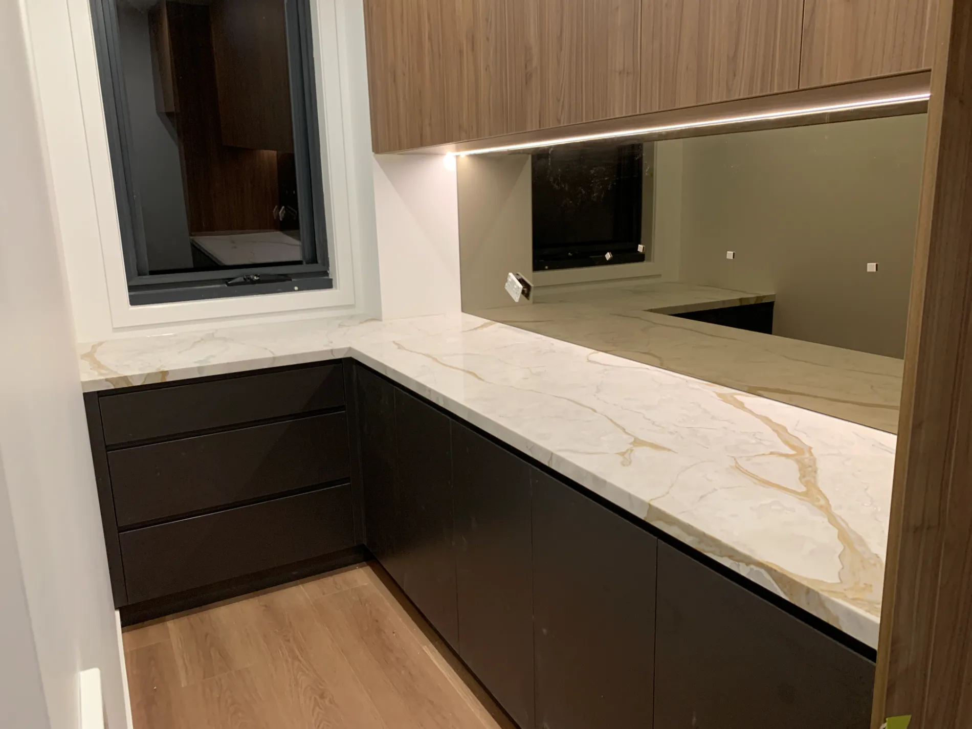 Luxury kitchen renovation with marble-look tiles and engineered stone countertops.